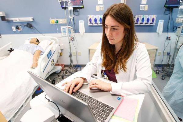 Nurse smiling in front of a computer.